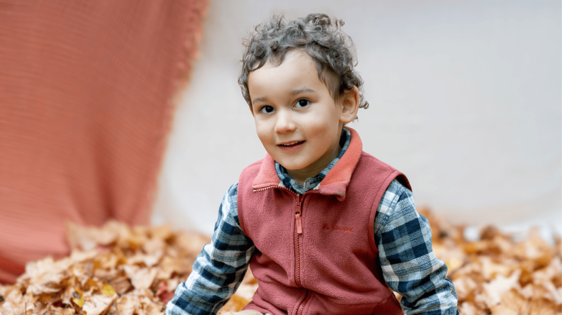 Kind Blätter draußen Kitafotografie Lächeln natürlich