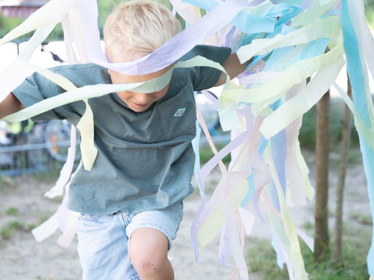 Kind spielt draußen mit bunten Bändern – Kita-Fotografie ohne Stress im Unterallgäu