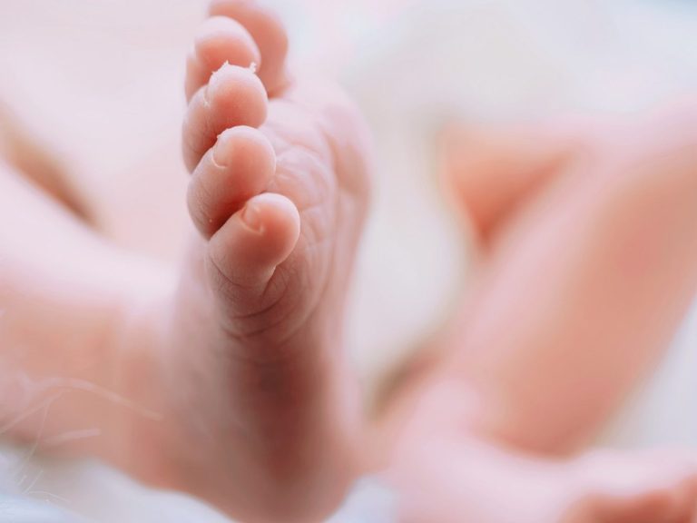 Viele Hände um ein schlafendes Neugeborenes – Newborn-Shooting zuhause im Unterallgäu